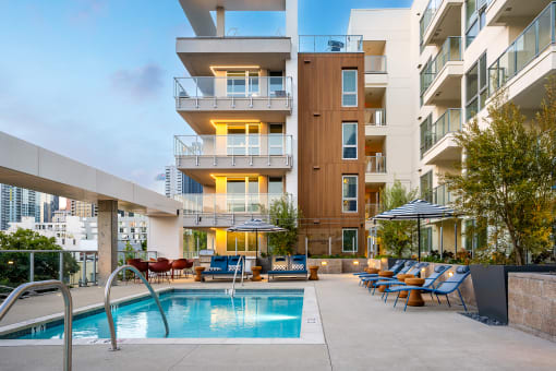 an outdoor swimming pool with chaise lounge chairs and sun umbrellas in front of an