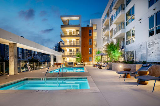 an outdoor swimming pool with chaise lounge chairs and a building in the background