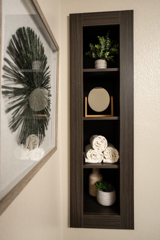 a shelf in a bathroom with a picture on the wall