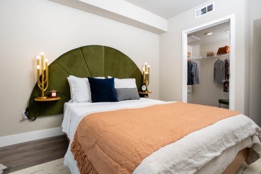 One-Bedroom Apartments in South Park Los Angeles, CA - The Emerald - Furnished Bedroom with Green Headboard, Spacious Closet, and Luxury Plank Flooring