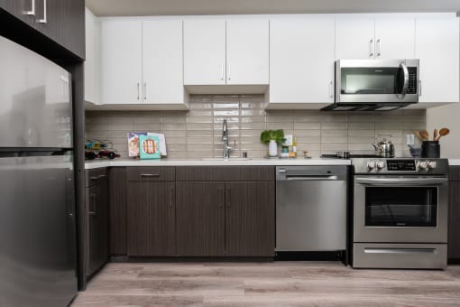 Apartments In DTLA For Rent - Kitchen With Stainless-Steel Appliances, White Cabinets, And Wood-Style Floors