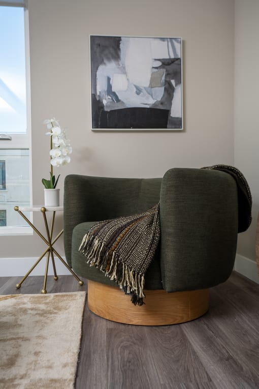 a living room with a green chair and a white orchid in a white vase