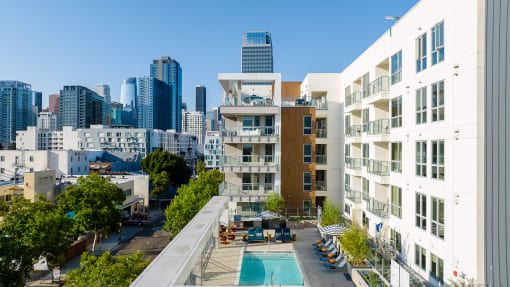 an aerial view of an apartment complex with a swimming pool and a city skyline in the background