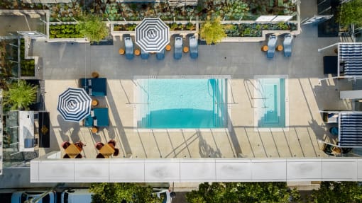 an aerial view of a pool and patio with umbrellas