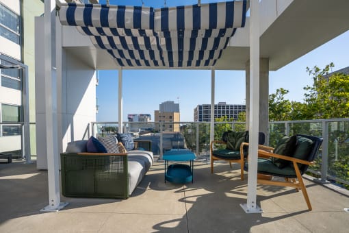 a pergola on a balcony with furniture and a view of the city