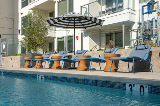 a poolside deck with lounge chairs and an umbrella