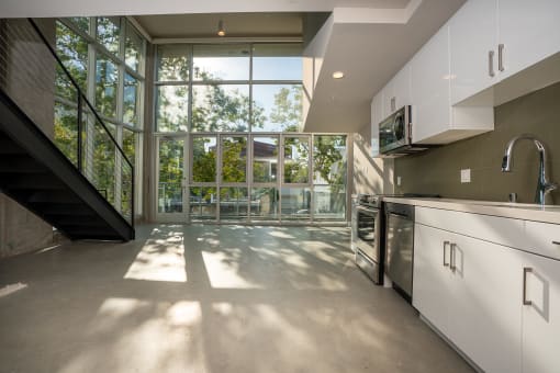 a kitchen with white cabinets and a large window