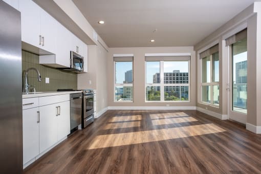 a kitchen and living room with hardwood floors and large windows