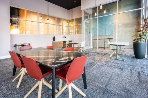 a conference room with a glass table and red chairs