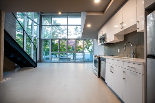 a kitchen with white cabinets and a large window