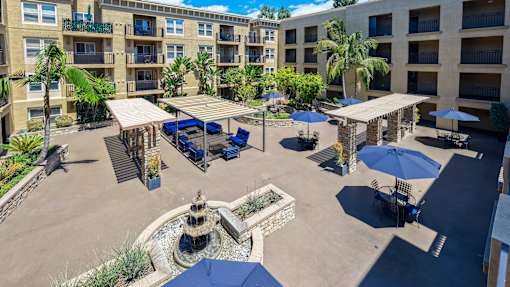 A sunny day at the outdoor seating area of a hotel with blue umbrellas and a fountain.