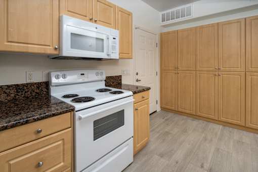 Cozy kitchen with brown cabinets and stove at 55+ FountainGlen Grand Isle, Murrieta, 92562