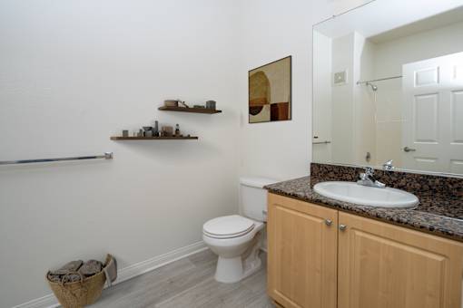Compact bathroom with wooden side table at 55+ FountainGlen Grand Isle, Murrieta, CA 92562