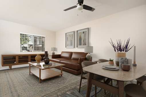 A living room with a brown couch, a coffee table, and a ceiling fan. at 55+ FountainGlen Terra Vista, Rancho Cucamonga