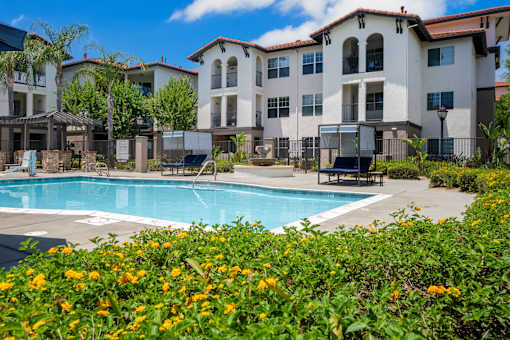A pool surrounded by flowers and a building in the background. at 55+ FountainGlen Terra Vista, California, 91730