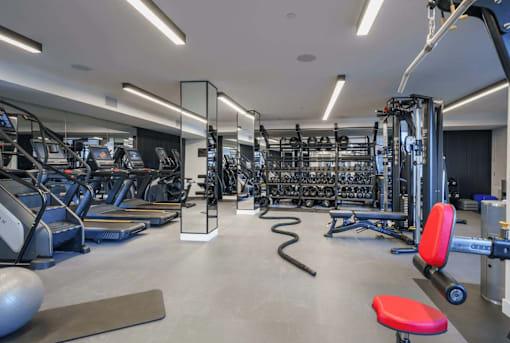 A gym with a variety of equipment including treadmills, weights, and exercise machines.