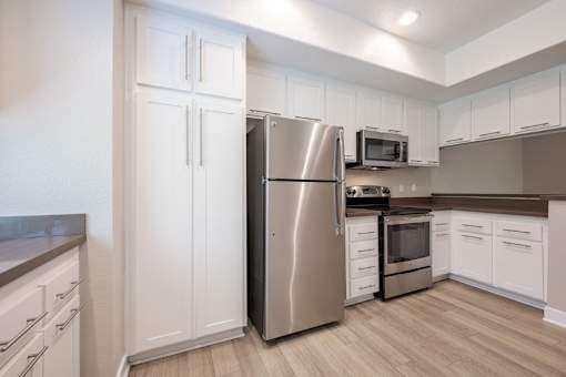 A kitchen with a stainless steel refrigerator, microwave, and oven.