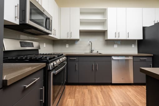 a kitchen with stainless steel appliances and white cabinets and dark bottom cabinets at Imperial Hardware Lofts, Riverside