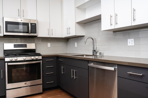 Kitchen with white upper cabinets and stainless appliances at Imperial Hardware Lofts, Riverside, 92501