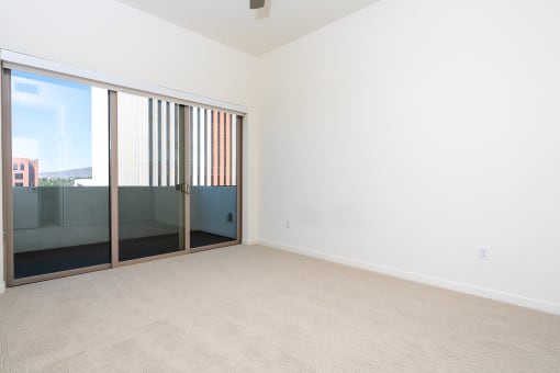 an empty living room with sliding glass doors to a balcony. at Imperial Hardware Lofts, Riverside, CA, 92501