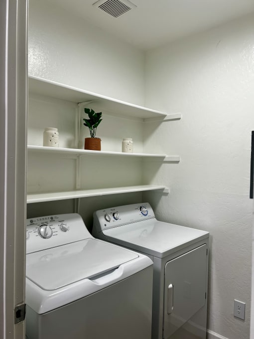 a white washer and dryer in a laundry room with shelves