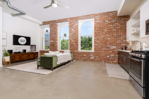 a living room with a couch and a brick wall and a kitchen with a stove at Imperial Hardware Lofts, California, 92501