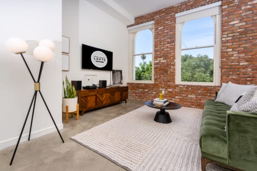 a living room with a green couch and a brick wall at Imperial Hardware Lofts, Riverside, CA