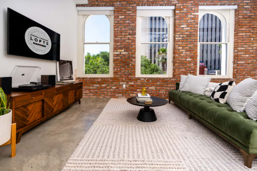 a living room with a green couch and a brick wall at Imperial Hardware Lofts, Riverside