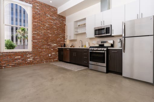 a kitchen with a brick wall and stainless steel appliances at Imperial Hardware Lofts, Riverside, 92501
