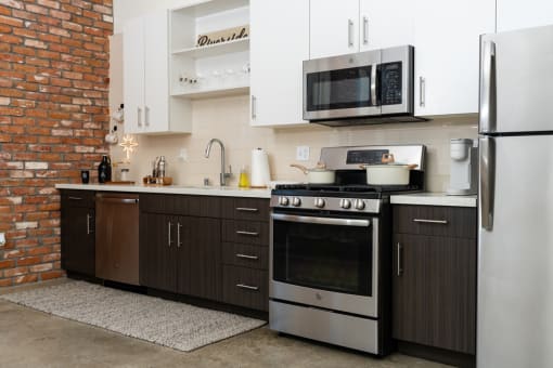 a kitchen with stainless steel appliances and white cabinets at Imperial Hardware Lofts, California, 92501