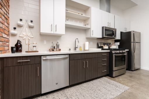 a kitchen with stainless steel appliances and white cabinets at Imperial Hardware Lofts, California, 92501