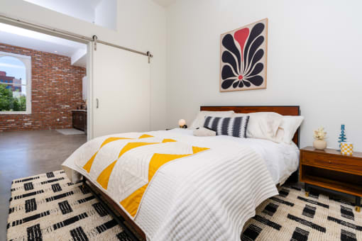 a bedroom with a bed and a red brick wall at Imperial Hardware Lofts, Riverside, CA