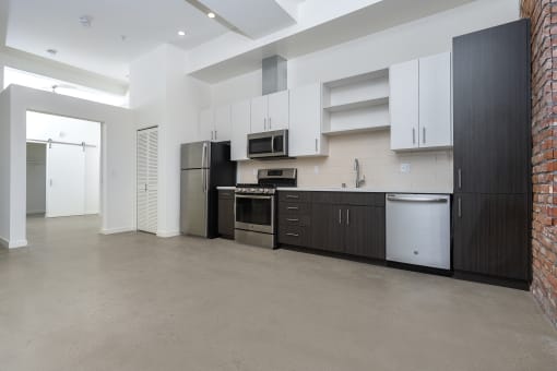 Kitchen with stainless appliances, white upper cabinets and dark lower cabinets at Imperial Hardware Lofts, Riverside, CA, 92501