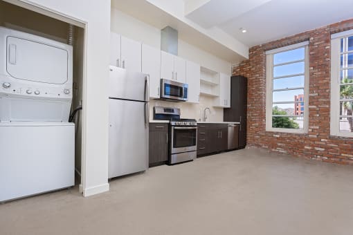 kitchen and laundry area with brick wall and large windows at Imperial Hardware Lofts, California