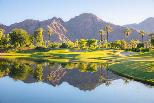 Two-Bedroom Townhomes in Corona, CA - Dos Lagos Townhomes - A View of the Lush Green Golf Course with Mountains in the Background, Lined with Trees, Sand Traps, and a Pond.