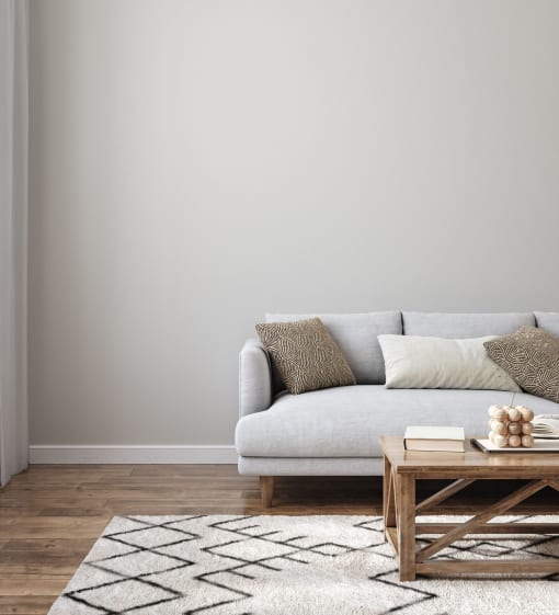 a living room with a white couch and a wooden coffee table in front of a gray wall