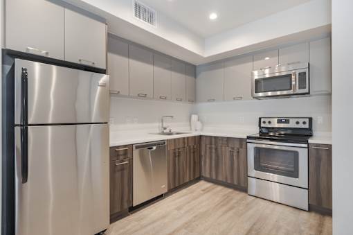A modern kitchen with stainless steel appliances and wooden cabinets at Wilshire Valencia Apartment, Los Angeles, CA, 90017