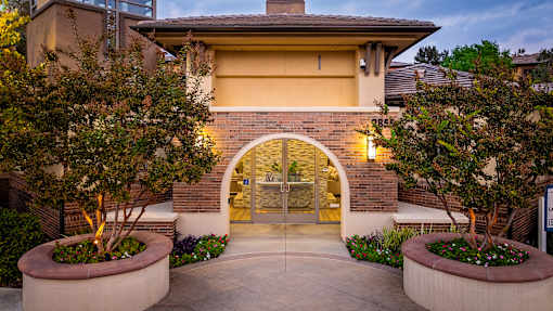 A house with a lit up entrance and a small tree in a planter.