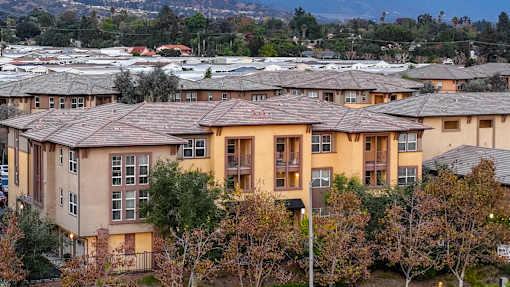 Apartment complex with brown roofs and trees in front.