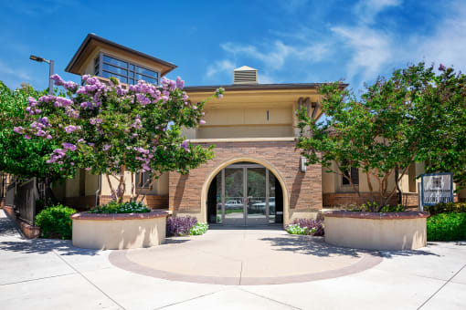 a building with an arched doorway and two large trees in front of it