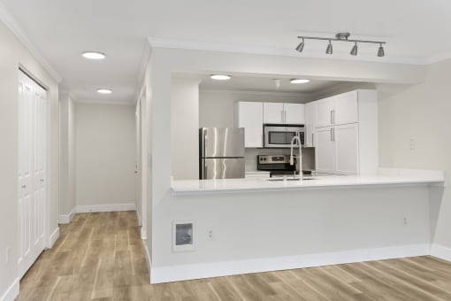 a kitchen with white cabinetry and a white counter top and stainless appliances