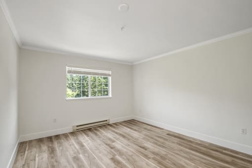 an empty bedroom with wood style flooring and a window