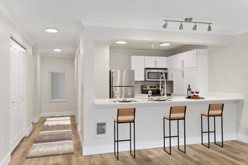 a kitchen with a breakfast bar, bar stool, white cabinetry and stainless appliances