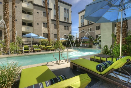 Resort-style pool with fountains and chaise lounge seating