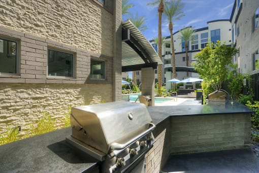 Apartments In Phoenix, AZ - Level At Sixteenth - BBQ Grills With Outdoor Seating, View Of Pool Area, And Palm Trees