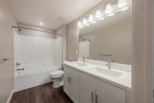A white bathroom with a toilet, sink, and mirror.