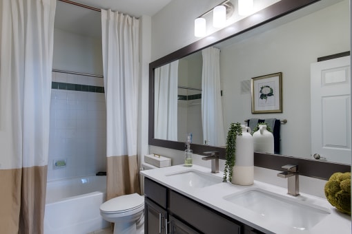 Plano, TX Apartments - McDermott Place - Bathroom With Double Sinks, Large Mirror, And Tile Bathtub Backsplash a bathtub