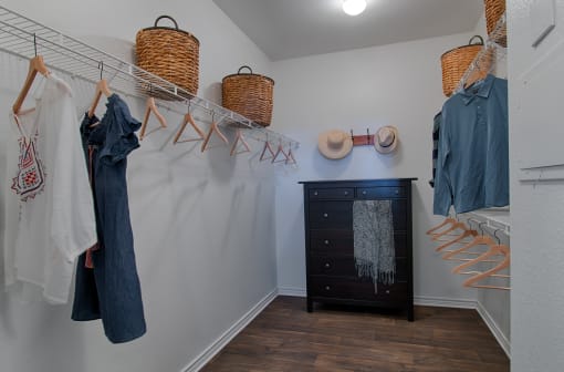 a walk in closet with a dresser and hangers