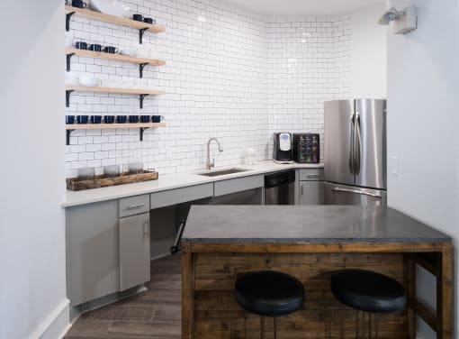 A kitchen with a bar stool and a refrigerator at McDermott Place, Plano, TX 75025