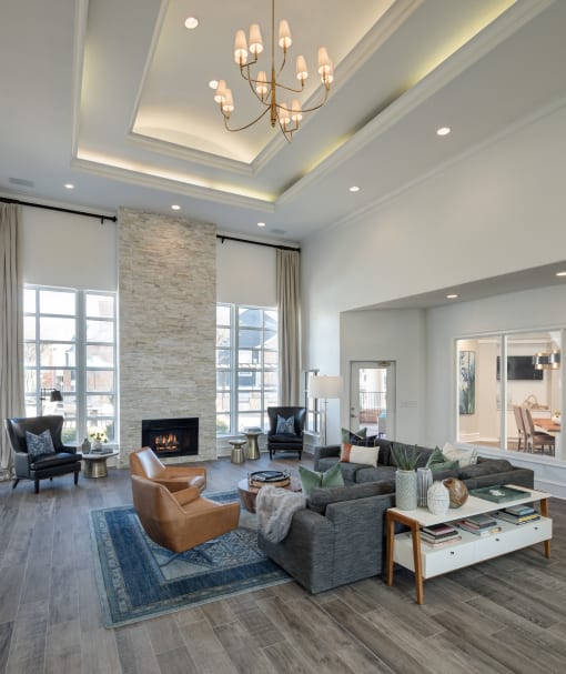 A modern living room with a stone fireplace and a chandelier at McDermott Place, Plano, 75025